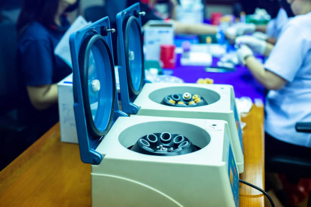 Selective focus to centrifuge machine for PRP with blurry nurse is drawing a patient's blood.